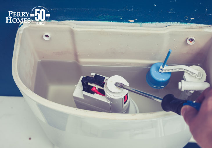 view of inside half-filled toilet tank with man holding srewdriver working on fill valve